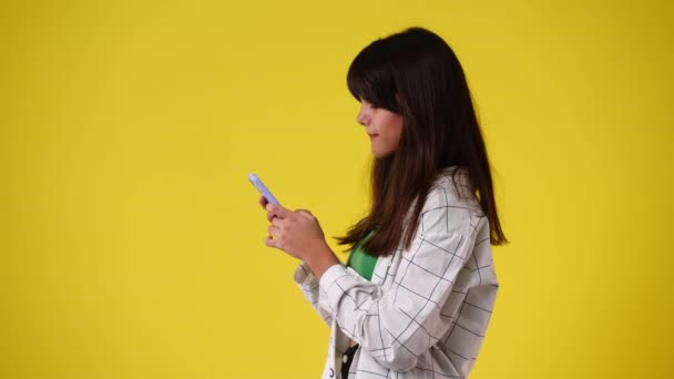 一个女孩在黄色背景下发送消息的4K视频 情绪的概念 — 图库视频影像