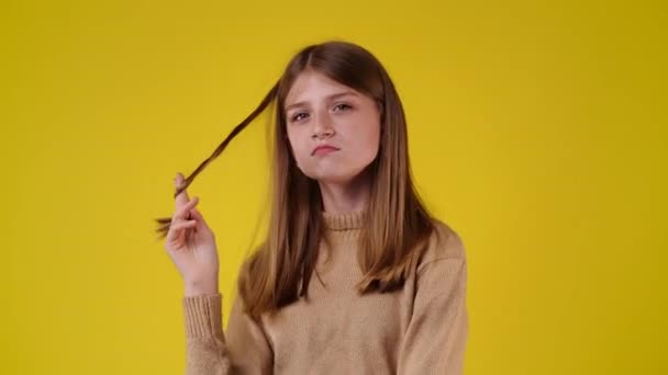 黄色の背景に隔離された髪に触れる女の子の4Kビデオ 感情の概念 — ストック動画