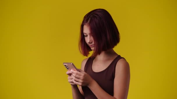 一个女孩在黄色背景下发送消息的4K视频 情绪的概念 — 图库视频影像