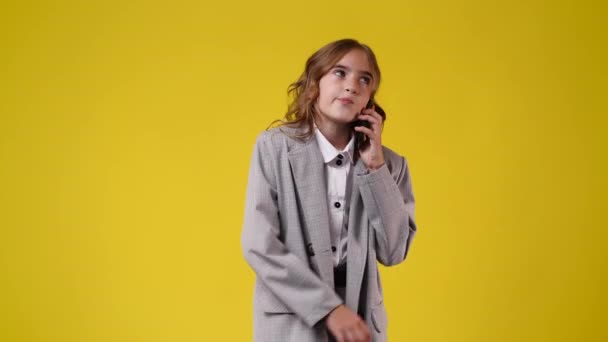 一个女孩在黄色背景下通过电话交谈的4K视频 情绪的概念 — 图库视频影像