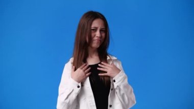 Mavi arka planda poz veren bir kızın 4K videosu. Duyguların kavramı.