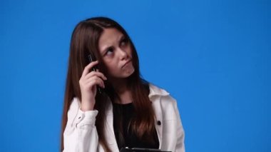 4k video of woman taking down some notes with a pen on blue background. Concept of emotions.