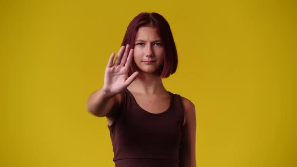 黄色の背景の上に停止標識を示す1人の女の子の4Kビデオ 感情の概念 — ストック動画