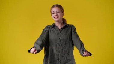 Sarı arka planda poz veren bir kızın 4K videosu. Duyguların kavramı.