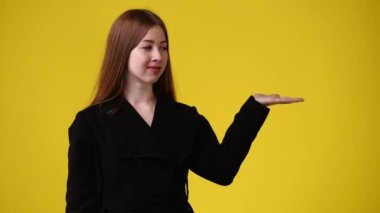 4k video of one girl pointing at left over yellow background. Concept of emotions.