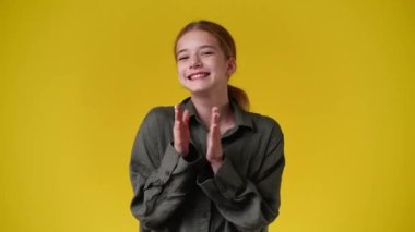 Sarı arka planda poz veren bir kızın 4K videosu. Duyguların kavramı.