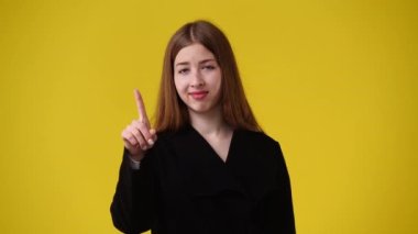 Sarı arka planda kurnaz yüz ifadesi olan bir kızın 4K videosu. Fikirleri olan kız kavramı.