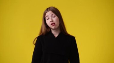 Sarı arka planda kurnaz yüz ifadesi olan bir kızın 4K videosu. Fikirleri olan kız kavramı.