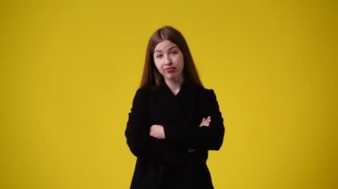 Sarı arka planda kurnaz yüz ifadesi olan bir kızın 4K videosu. Fikirleri olan kız kavramı.