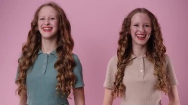 4k video of two twin girls smiling and looking at the camera. Concept of emotions.