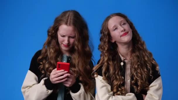 Video Von Zwillingsmädchen Mit Telefon Über Blauem Hintergrund Konzept Der — Stockvideo