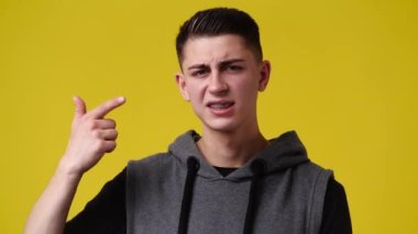 4k video of one man showing thumb down over yellow background. Concept of emotions.