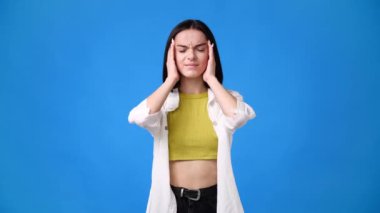 4k video of one girl having headache over blue background. Concept of emotions.