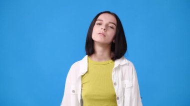 4k video of one girl having headache over blue background. Concept of emotions.
