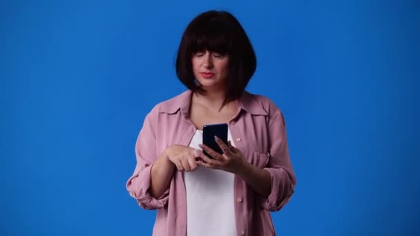 1人の女が左を向いて親指を青い背景に見せる4K動画 感情の概念 — ストック動画