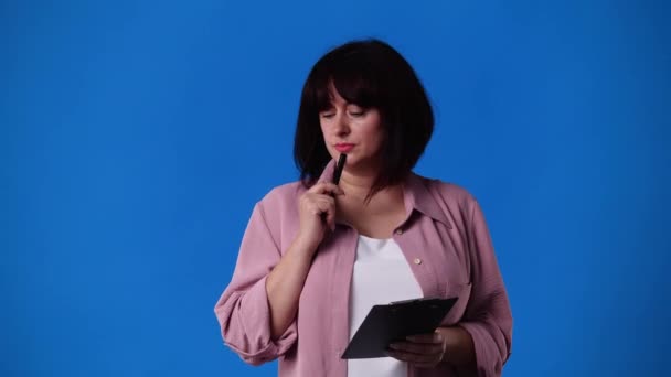 青色の背景にペンでいくつかのメモを取る女性の4Kビデオ 感情の概念 — ストック動画