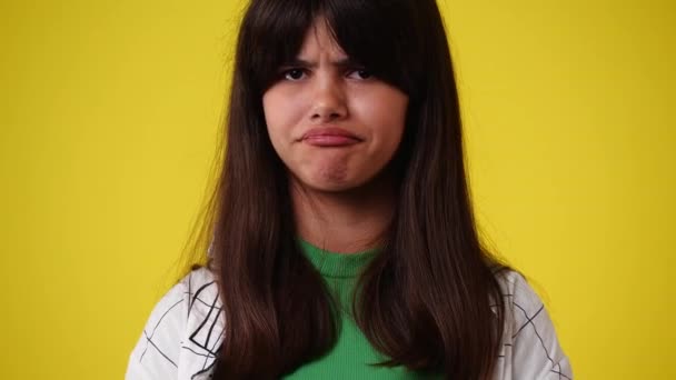 黄色い背景に否定的な表情をした1人の少女の4K動画 感情の概念 — ストック動画