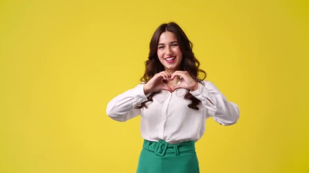 Video Jente Som Smiler Viser Hjertemerket Gul Bakgrunn Følelsesbegreper – stockvideo