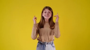 4k slow motion video of one girl showing thumbs up and smiling over yellow background. Concept of emotions.