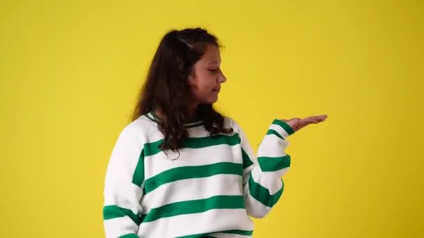 4K视频 一个年轻女孩指着手上的东西而不是黄色背景 情绪的概念 — 图库视频影像