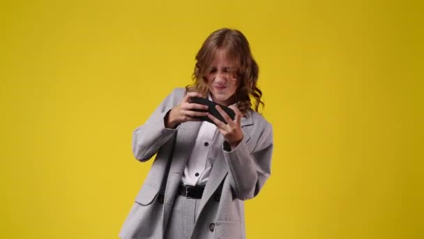Видео Одной Девушки Играет Телефоне Желтом Фоне Концепция Эмоций — стоковое видео