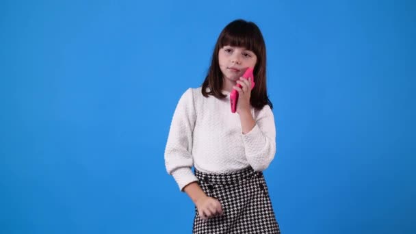 Genç Bir Kızın Mavi Arka Planda Biriyle Telefonda Konuşurken Videosu — Stok video