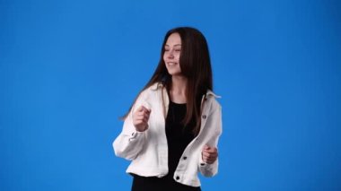 Mavi arka planda dans edip gülümseyen bir kızın 4K videosu. Duyguların kavramı.