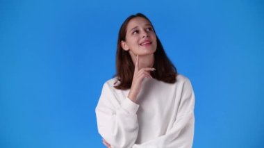 4k video of one girl who holding her chin and thinks about something on blue background. Concept of emotions.