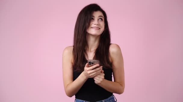 1人の女の子の4K動画で ピンクの背景に正の顔の表情が文字を打ちます 感情の概念 — ストック動画