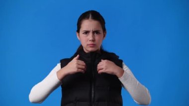 Mavi arka planda bir şeye negatif tepki veren bir kızın 4k videosu. Duyguların kavramı.
