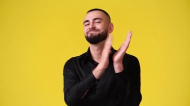 Sarı arka planda alkışlayan adamın 4K videosu. Duyguların kavramı.