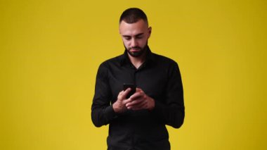 Sarı arka planda telefonu kullanan bir adamın 4K videosu. Duygu kavramı.