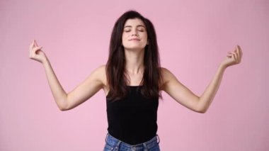 Pembe arka planda poz veren bir kızın 4K videosu. Duyguların kavramı.