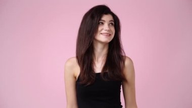 Pembe arka planda poz veren bir kızın 4K videosu. Duyguların kavramı.