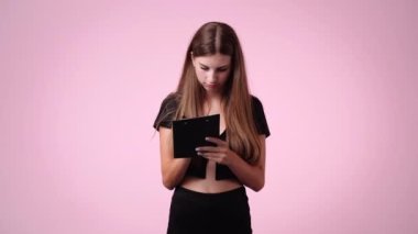 Pembe arka planda poz veren bir kızın 4K videosu. Duyguların kavramı.