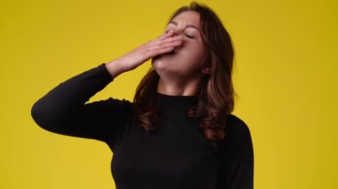 Sarı arka planda kurnaz yüz ifadesi olan bir kızın 4K videosu. Fikirleri olan kız kavramı.