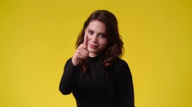 Sarı arka planda kurnaz yüz ifadesi olan bir kızın 4K videosu. Fikirleri olan kız kavramı.