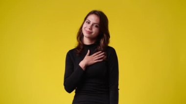 Sarı arka planda yan yana bakan bir kızın 4k videosu. Duyguların kavramı.