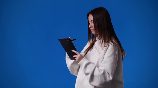 青い背景の上にノートを取る1人の女の子の4Kビデオ 感情の概念 — ストック動画