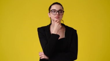 Sarı arka planda düşünceli yüz ifadesi olan bir kızın 4K videosu. Fikirleri olan kız kavramı.