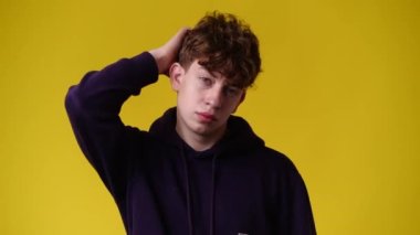 Sarı arka planda düşünceli yüz ifadesi olan bir adamın 4K videosu. Fikirleri olan insan kavramı.