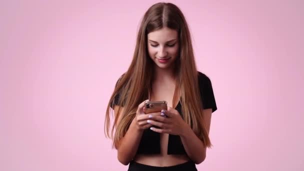 ピンクの背景にテキストを入力する1人の女の子の4Kビデオ 感情の概念 — ストック動画