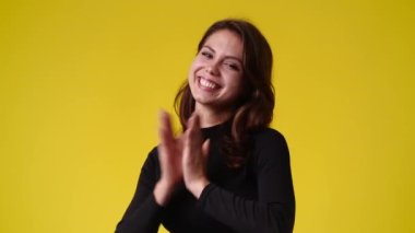 Sarı arka planda kurnaz yüz ifadesi olan bir kızın 4K videosu. Fikirleri olan kız kavramı.
