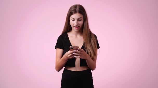 ピンクの背景に否定的な顔の表情で電話で話している1人の女の子の4Kビデオ 感情の概念 — ストック動画