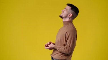 Sarı arka plandaki bir video için poz veren bir adamın 4K videosu. Duyguların kavramı.