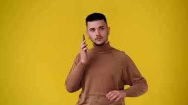 4k video of one man using phone over yellow background. Concept of emotion.