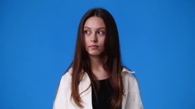 4k video of one girl showing silence sign on blue background. Concept of emotions.