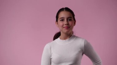 Pembe arka planda gülümseyen bir kızın 4K yavaş çekim videosu. Duyguların kavramı.