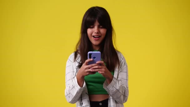 1人の女の子が何かを考えて黄色の背景にテキストを入力する4Kビデオ 感情の概念 — ストック動画