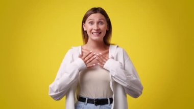 Sarı arka planda sevinen ve kollarını kavuşturan bir kadının 4k yavaş çekim videosu. Duyguların kavramı.